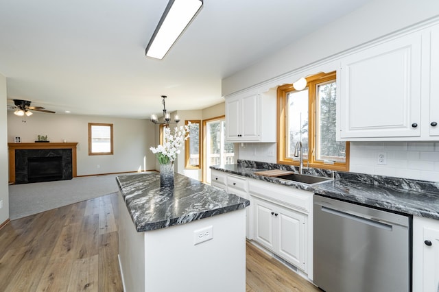 kitchen featuring light wood-style flooring, a sink, tasteful backsplash, a center island, and dishwasher