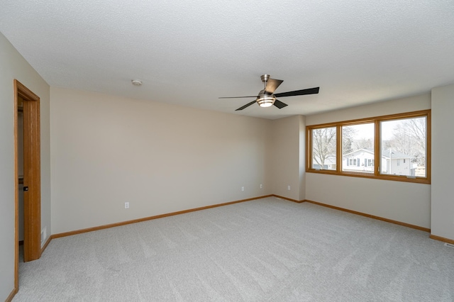 unfurnished room with a textured ceiling, a ceiling fan, light colored carpet, and baseboards