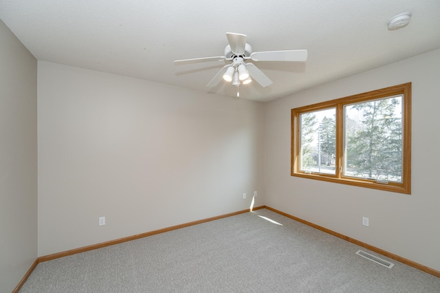 spare room with visible vents, carpet flooring, baseboards, and ceiling fan