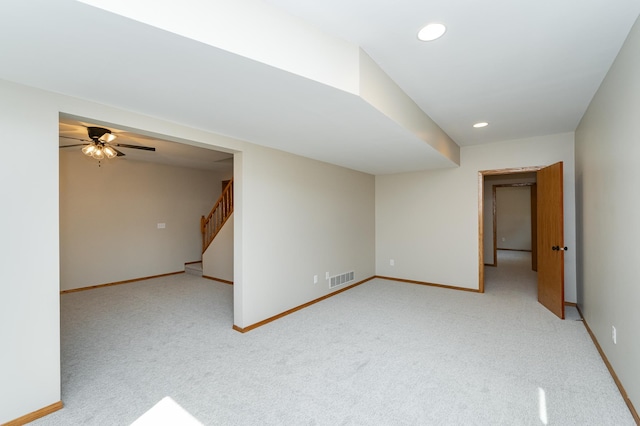 spare room featuring visible vents, light carpet, baseboards, and stairway