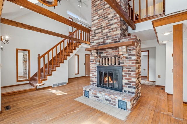 unfurnished living room with a brick fireplace, wood-type flooring, and visible vents