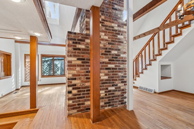 staircase featuring a high ceiling, wood-type flooring, visible vents, and baseboards