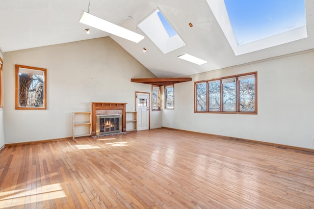 unfurnished living room with high vaulted ceiling, light wood-style flooring, a premium fireplace, and baseboards