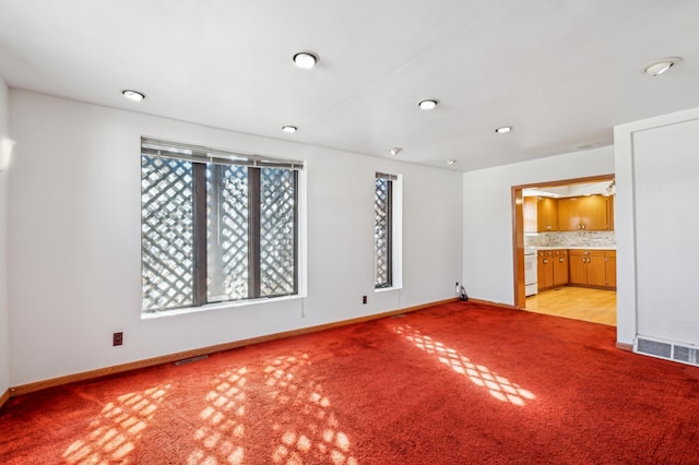 spare room with light carpet, visible vents, and baseboards