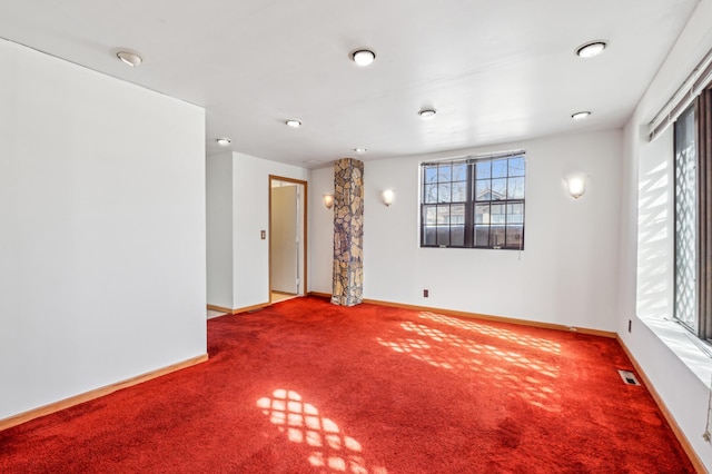 carpeted spare room featuring visible vents and baseboards