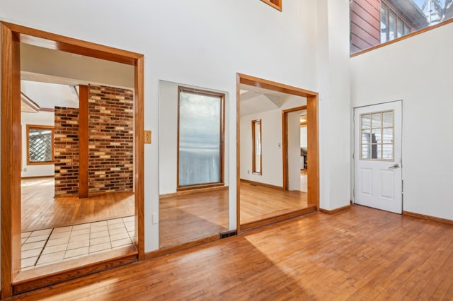 foyer with visible vents, a high ceiling, hardwood / wood-style flooring, and baseboards