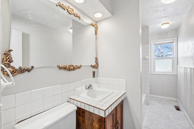 bathroom with a textured ceiling, toilet, a sink, and visible vents