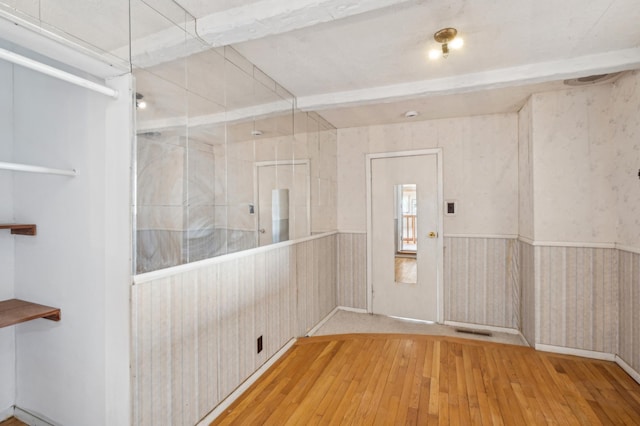 interior space featuring light wood-style flooring, visible vents, and wainscoting