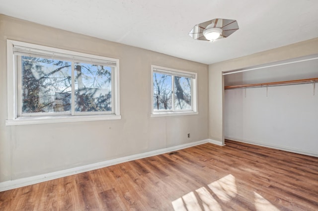 unfurnished bedroom with a closet, light wood-type flooring, visible vents, and baseboards