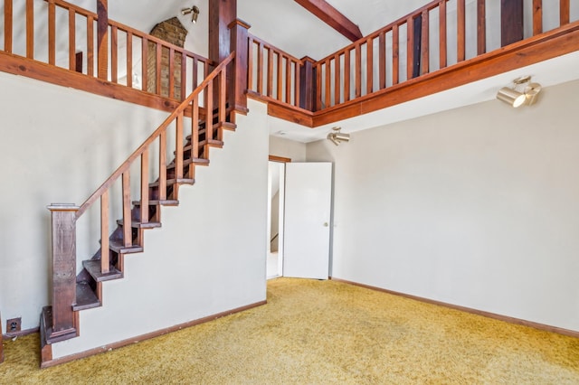 staircase with a towering ceiling, baseboards, and carpet flooring