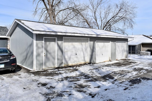 snow covered garage with a detached garage