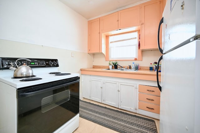 kitchen with electric range, freestanding refrigerator, light countertops, a sink, and light tile patterned flooring