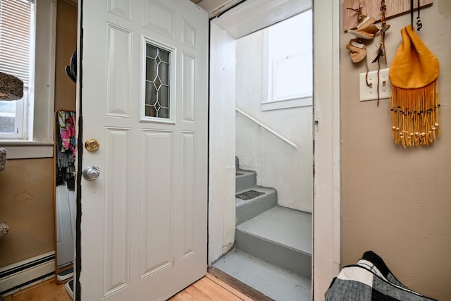 foyer entrance with a baseboard heating unit, light wood-style floors, and stairs