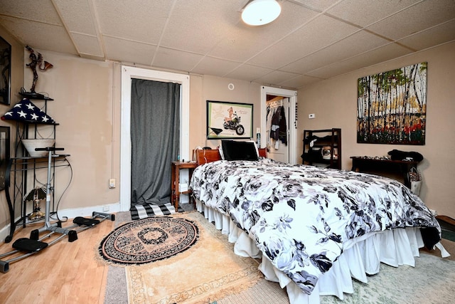 bedroom with a drop ceiling, baseboards, and wood finished floors