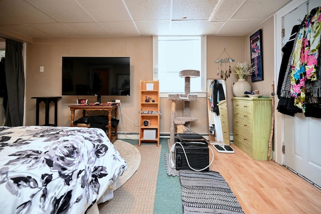 bedroom featuring a drop ceiling and wood finished floors