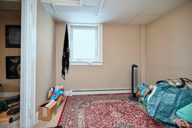 interior space with a paneled ceiling, carpet, and a baseboard radiator