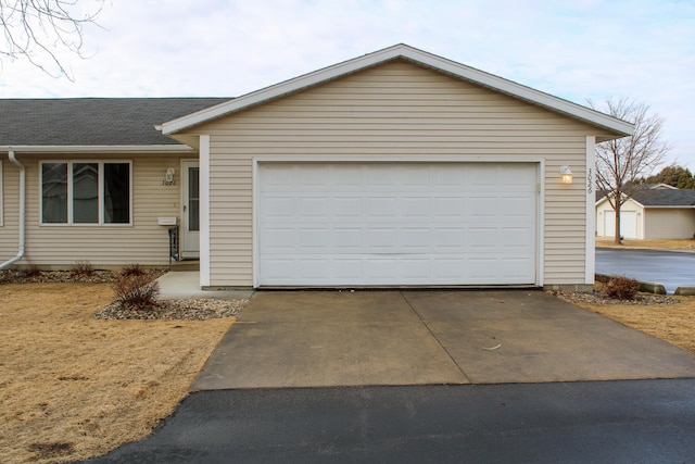 view of front of home featuring driveway, roof with shingles, and an attached garage