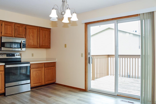 kitchen featuring light wood-style floors, light countertops, appliances with stainless steel finishes, brown cabinets, and decorative light fixtures