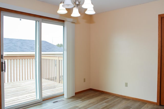 empty room featuring baseboards, visible vents, a water view, light wood-type flooring, and a notable chandelier