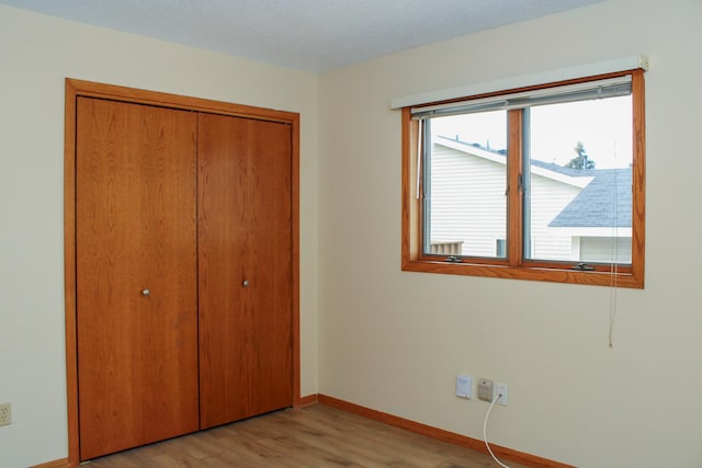 unfurnished bedroom with a closet, light wood-style flooring, and baseboards