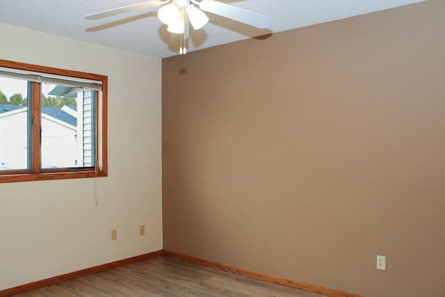 empty room featuring light wood-type flooring, a ceiling fan, and baseboards