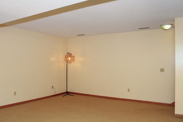 empty room featuring baseboards, a textured ceiling, and light colored carpet