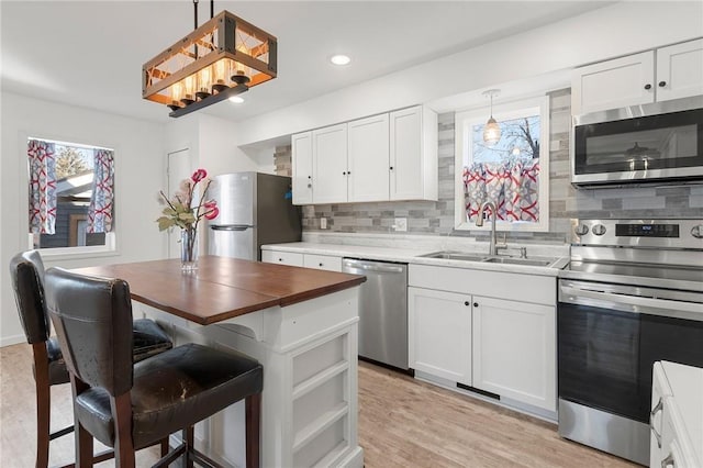 kitchen featuring stainless steel appliances, light wood-style floors, a wealth of natural light, and a sink