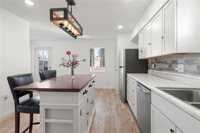 kitchen featuring stainless steel appliances, backsplash, a wealth of natural light, and white cabinets