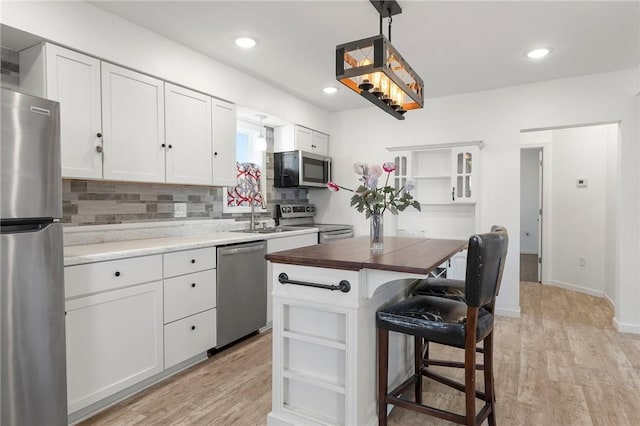 kitchen with open shelves, light wood-style flooring, and stainless steel appliances