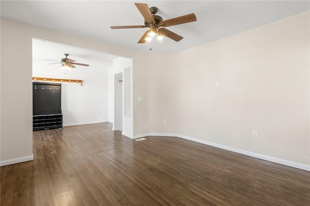 unfurnished living room featuring ceiling fan, dark wood finished floors, and baseboards