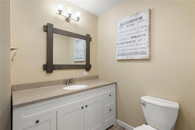 bathroom featuring toilet, baseboards, and vanity