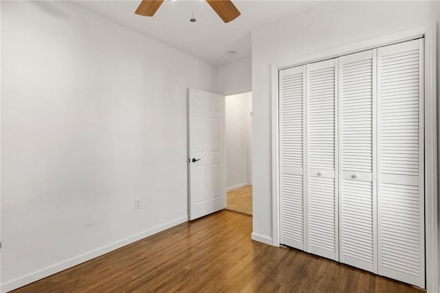 unfurnished bedroom featuring dark wood-style floors, a ceiling fan, baseboards, and a closet