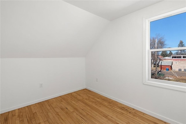 bonus room featuring vaulted ceiling, light wood-style flooring, and baseboards