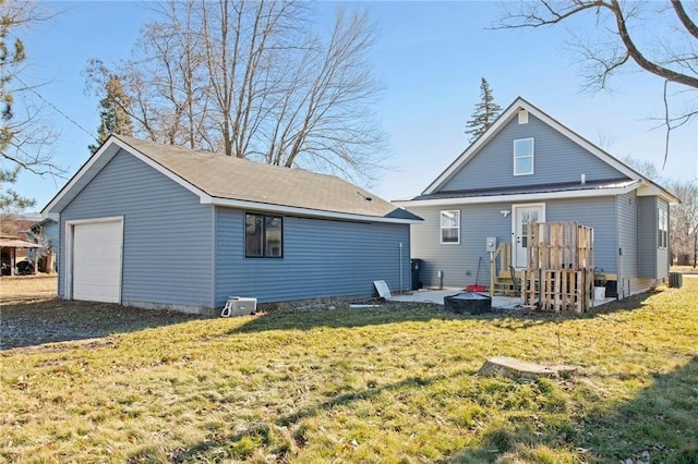 back of property featuring a patio area, a detached garage, and a lawn