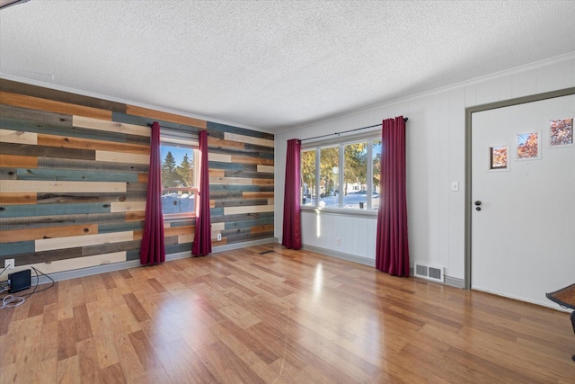 interior space featuring a textured ceiling, visible vents, and wood finished floors