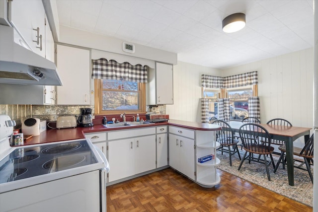 kitchen with white electric range oven, dark countertops, white cabinetry, a sink, and under cabinet range hood