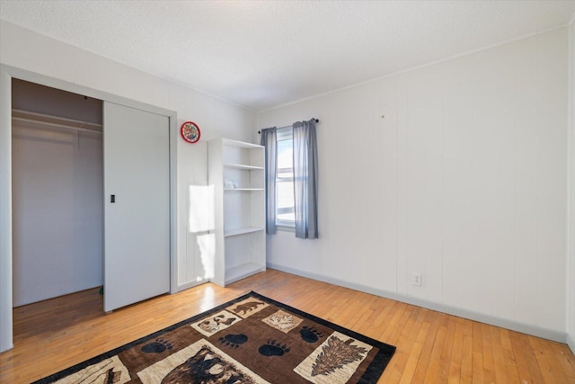 bedroom featuring wood-type flooring, a textured ceiling, and a closet