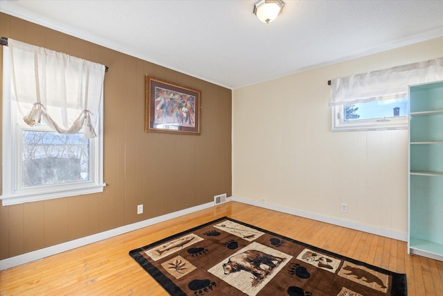 interior space featuring hardwood / wood-style flooring, baseboards, and visible vents