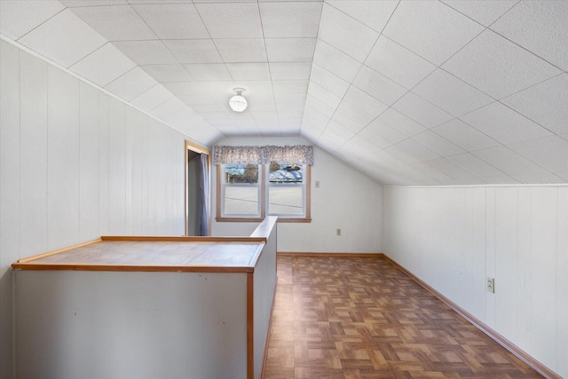 bonus room with lofted ceiling and wooden walls