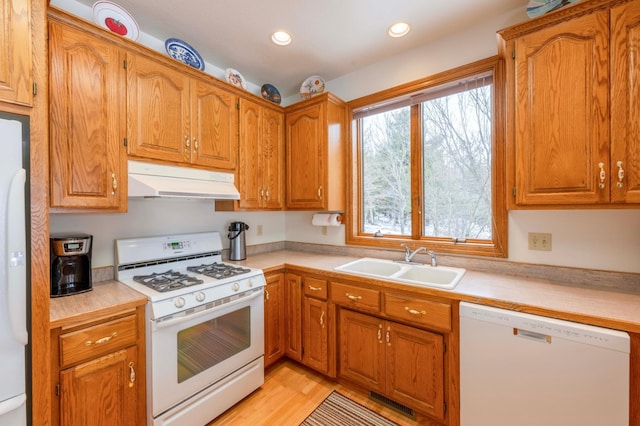 kitchen featuring white appliances, under cabinet range hood, light countertops, and a sink