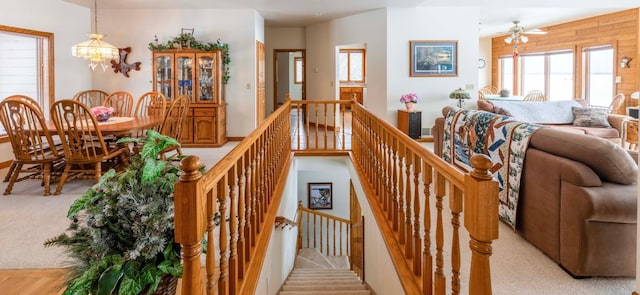 stairs featuring ceiling fan with notable chandelier and carpet flooring