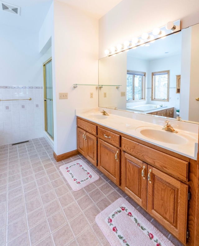 bathroom featuring a garden tub, double vanity, a sink, and visible vents