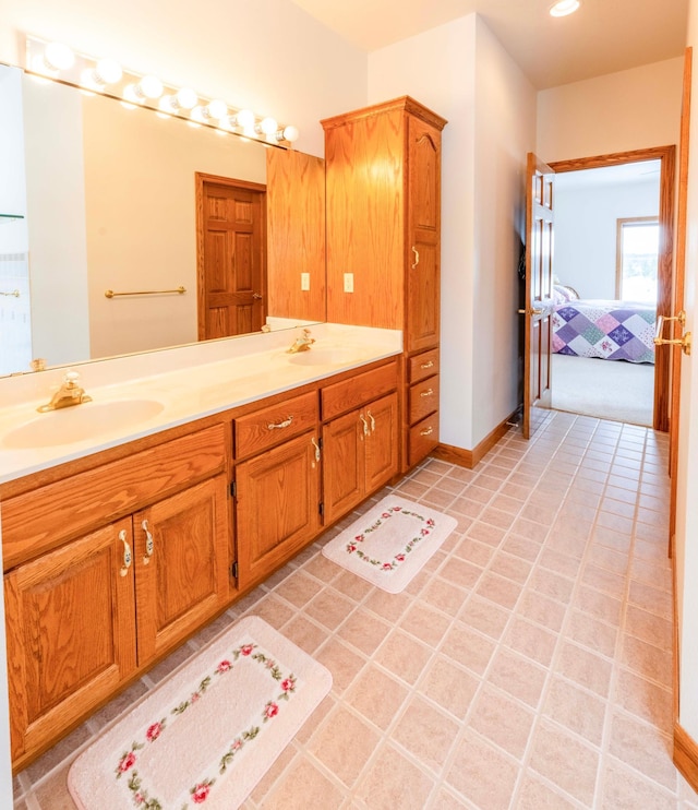 ensuite bathroom featuring double vanity, baseboards, a sink, and ensuite bathroom