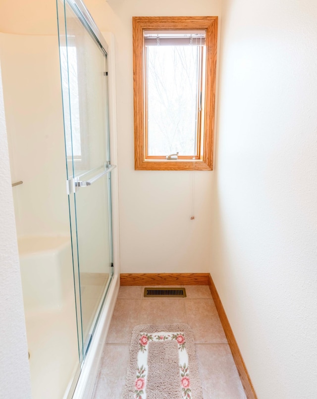 bathroom featuring a stall shower, tile patterned floors, visible vents, and baseboards