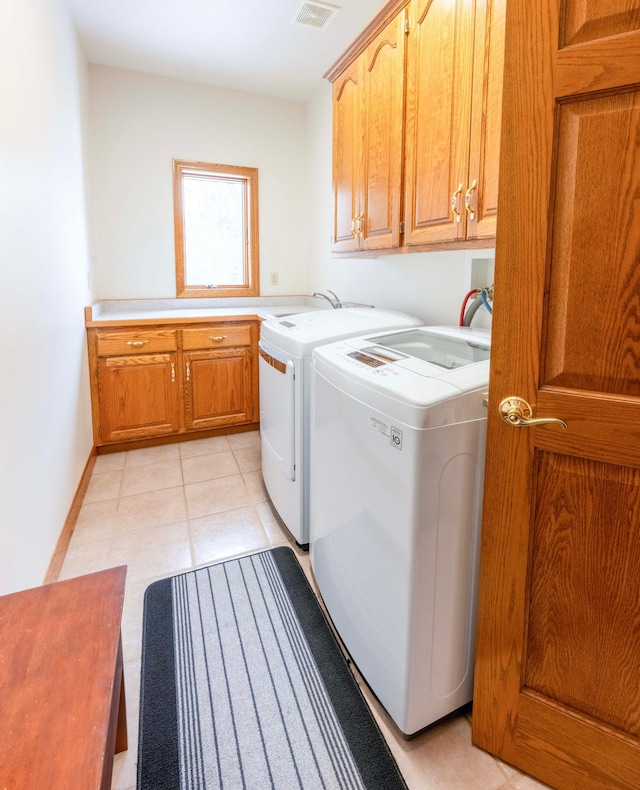 laundry room with washing machine and clothes dryer, light tile patterned floors, cabinet space, visible vents, and baseboards