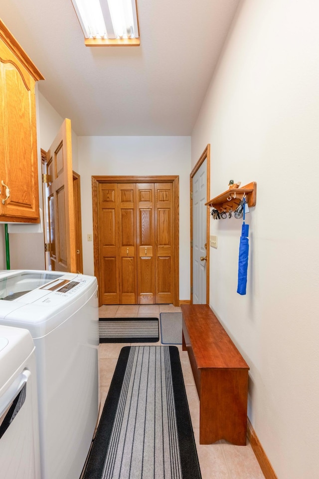 laundry area featuring cabinet space, light tile patterned floors, baseboards, and separate washer and dryer