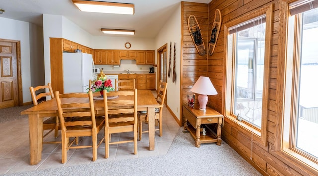 dining area with light tile patterned floors and wooden walls