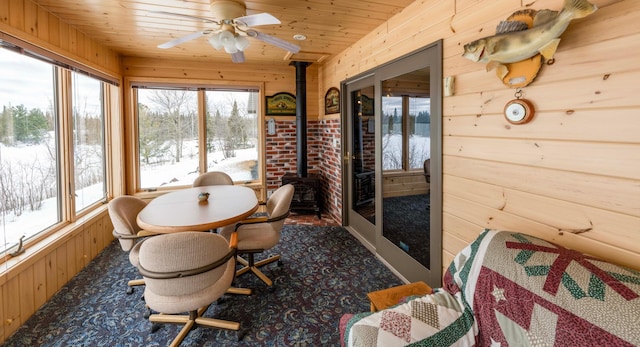 sunroom / solarium with a ceiling fan, wood ceiling, and a wood stove