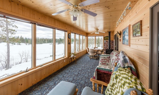 sunroom with a wood stove, wood ceiling, and a ceiling fan