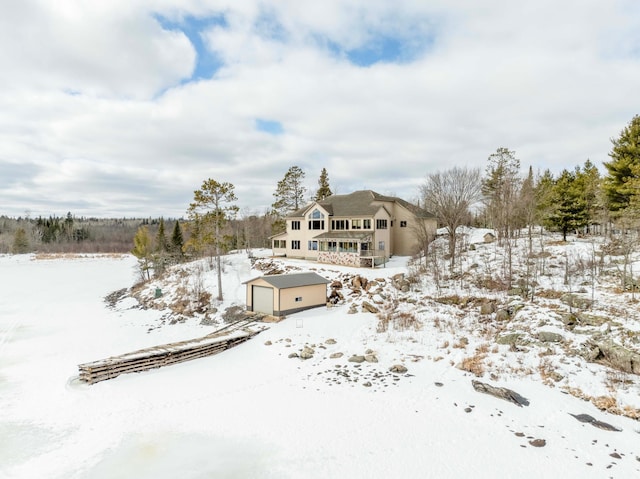 snow covered rear of property with an outdoor structure